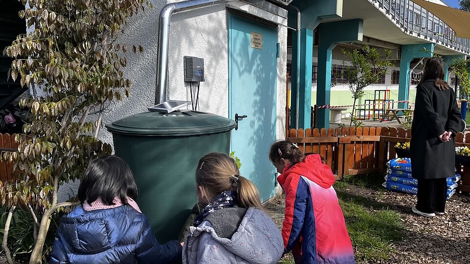 Die Kinder der Kita Goldfischchen in Berlin bewässern ihr Hochbeet im Kita-Garten mithilfe eines Gießroboters.