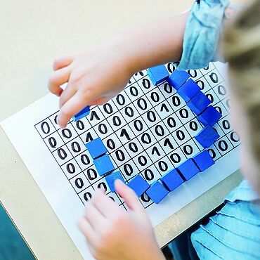 Auf dem Bild sieht man ein Mädchen, dass mit einer Informatik-Tafel spielt