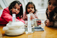 Drei Mädchen in der Kita beobachten ein Experiment zum Thema Wärme
