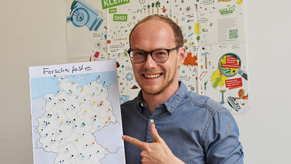 Der Projektleiter Raphael zeigt eine Deutschlandkarte mit Forscherfesten