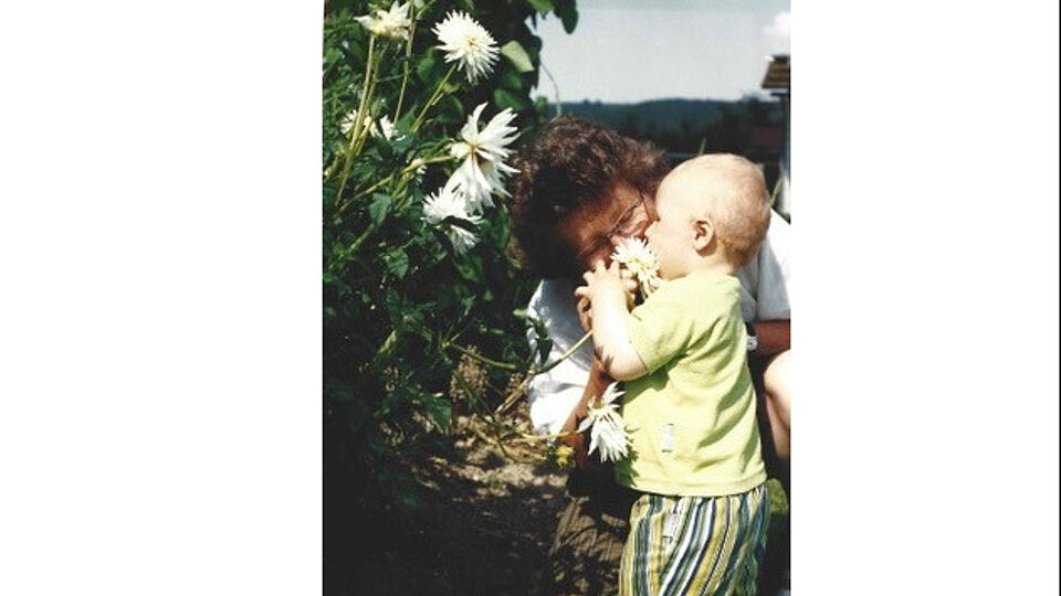 A toddler and his grandmother with some white flowers.