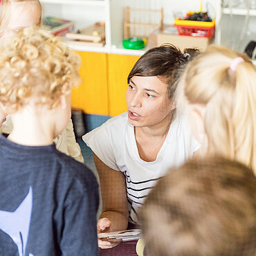 Eine Frau diskutiert mit Kindern auf Augenhöhe
