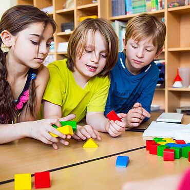 Grundschulkinder forschen mit Bausteinen unterschiedlichster Formen und Farben