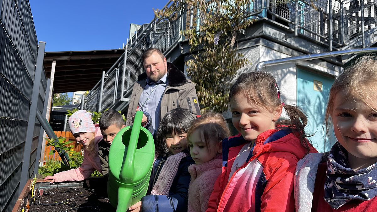 Die Kinder der Kita Goldfischchen in Berlin bewässern ihr Hochbeet im Kita-Garten mithilfe eines Gießroboters.