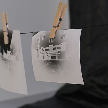 Zwei entwickelte Schwarz-weiß-Fotos hängen auf einer Wäscheleine.