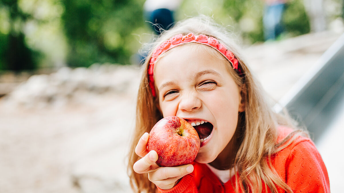 Kind beißt in einen rotel Apfel