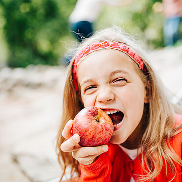 Kind beißt in einen rotel Apfel