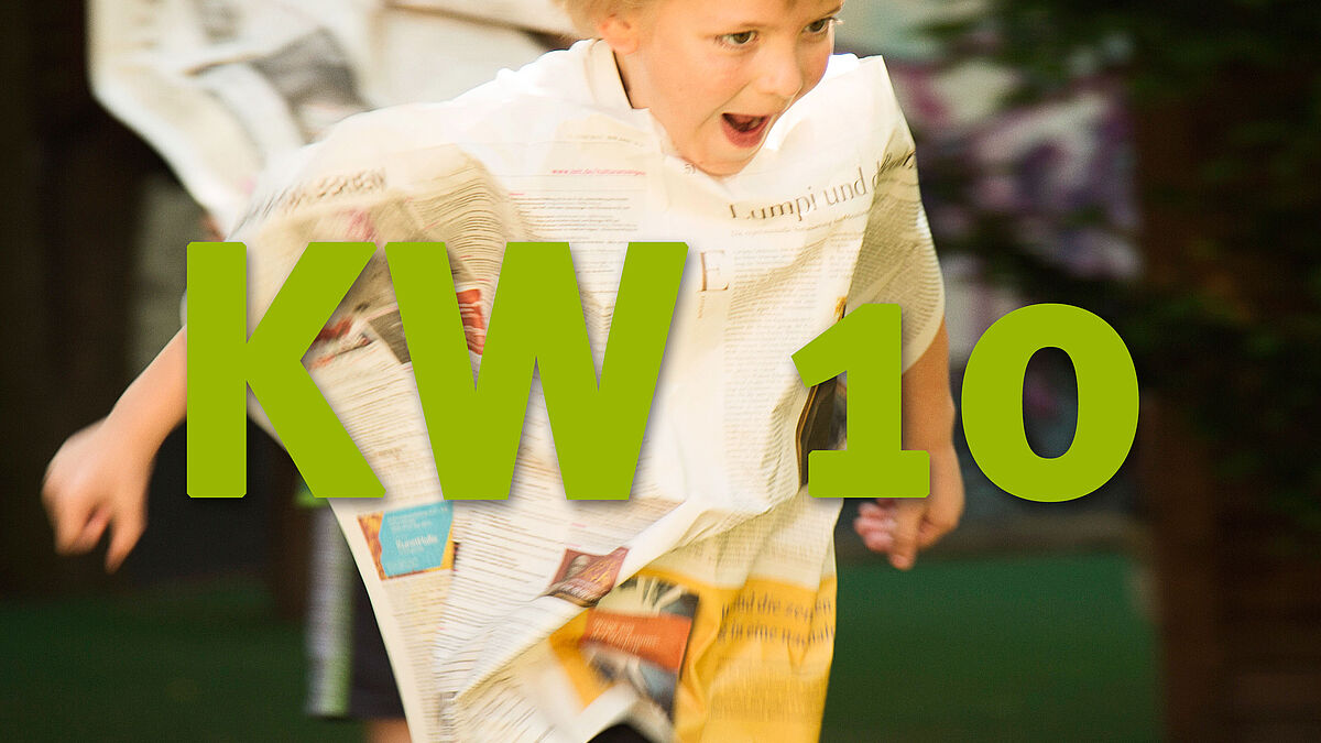 Ein Junge läuft grinsend mit einer Zeitung vor seinem Körper